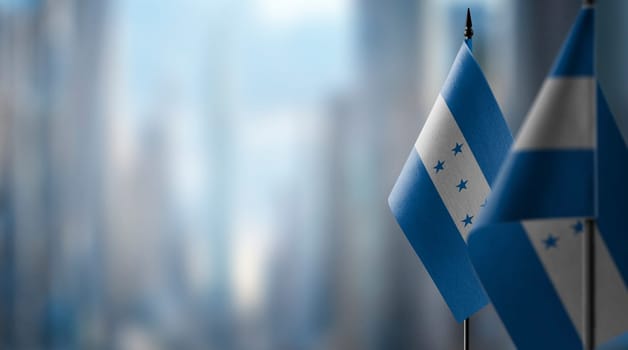 Small flags of the Honduras on an abstract blurry background.