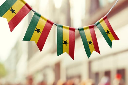 A garland of Ghana national flags on an abstract blurred background.
