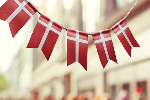 A garland of Denmark national flags on an abstract blurred background.
