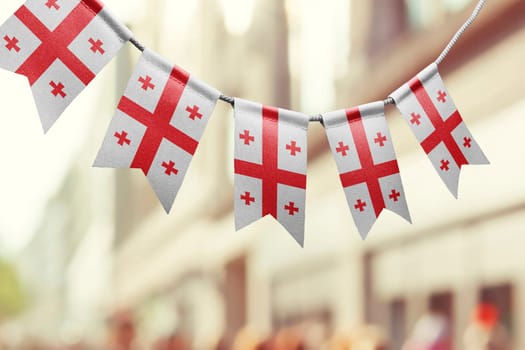 A garland of Georgia national flags on an abstract blurred background.