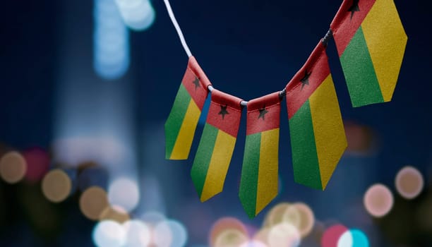 A garland of Guinea Bissau national flags on an abstract blurred background.