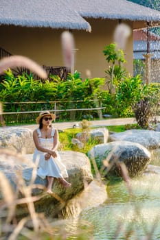 Asian women relaxing by a water pond in Khao Yai Thailand at sunset.