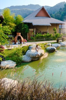 Asian women relaxing by a water pond in Khao Yai Thailand at sunset.