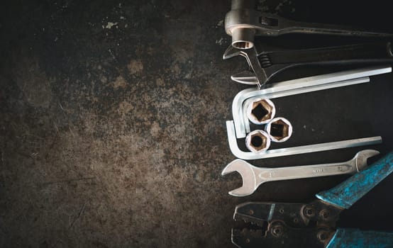 Hand tools consisting of wrenches, pliers, socket wrenches, laid out on old steel plate background.