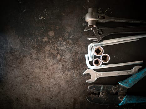 Hand tools consisting of wrenches, pliers, socket wrenches, laid out on old steel plate background.