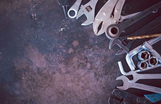Hand tools consisting of wrenches, pliers, socket wrenches, laid out on old steel plate background.