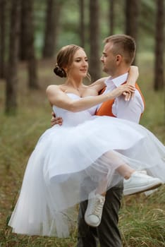 young couple bride in a white short dress and groom in a gray suit in a pine forest among the trees