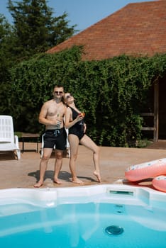 guy and a girl in bathing suits are relaxing, sunbathing and having fun near the blue pool