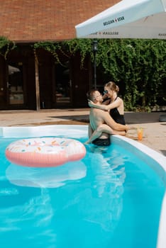 guy and a girl in bathing suits are relaxing, sunbathing and having fun near the blue pool