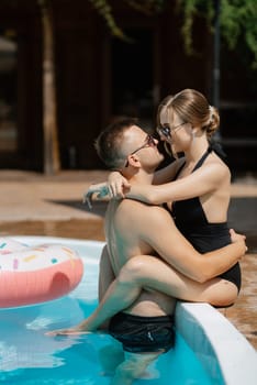 guy and a girl in bathing suits are relaxing, sunbathing and having fun near the blue pool