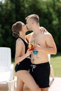 guy and a girl in bathing suits are relaxing, sunbathing and having fun near the blue pool