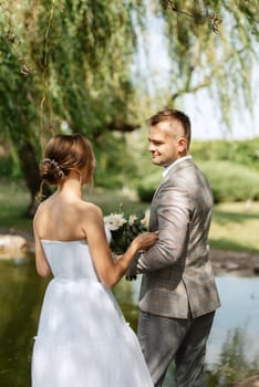 the first meeting of the bride and groom in wedding outfits in the park