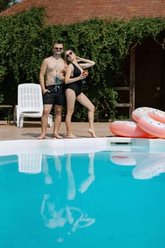 guy and a girl in bathing suits are relaxing, sunbathing and having fun near the blue pool