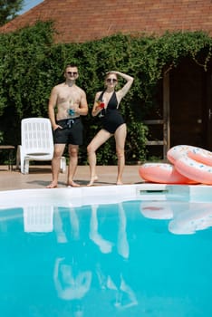 guy and a girl in bathing suits are relaxing, sunbathing and having fun near the blue pool