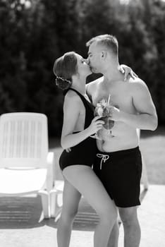 guy and a girl in bathing suits are relaxing, sunbathing and having fun near the blue pool