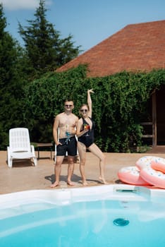 guy and a girl in bathing suits are relaxing, sunbathing and having fun near the blue pool