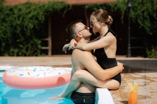 guy and a girl in bathing suits are relaxing, sunbathing and having fun near the blue pool