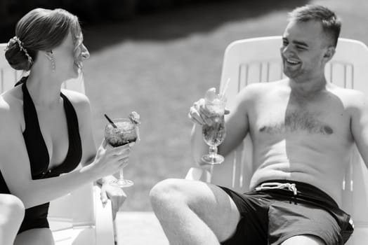 guy and a girl in bathing suits are relaxing, sunbathing and having fun near the blue pool