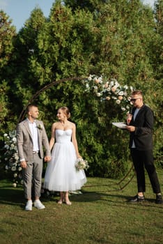 wedding ceremony of the newlyweds on the glade near the restaurant