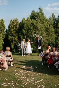 wedding ceremony of the newlyweds on the glade near the restaurant