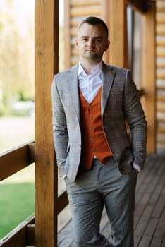 portrait of the groom in a gray suit and an orange vest and white sneakers