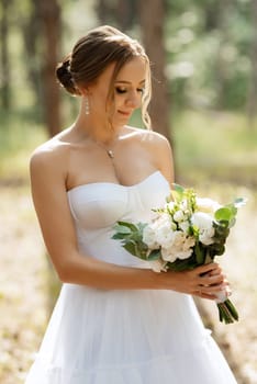 young bride in a white short dress in a spring pine forest among the trees