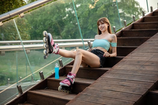 A young girl stretches her muscles after a workout. Smiling girl lifts straight leg up. Next to the girl stands a bottle of blue drink.