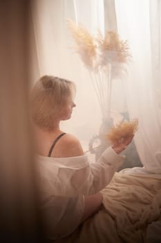 Portrait of sexual body positive adult lady woman in intimate in tender space indoors in a bedroom. Plump girl poses in black underwear and white shirt during boudoir style photo shoot