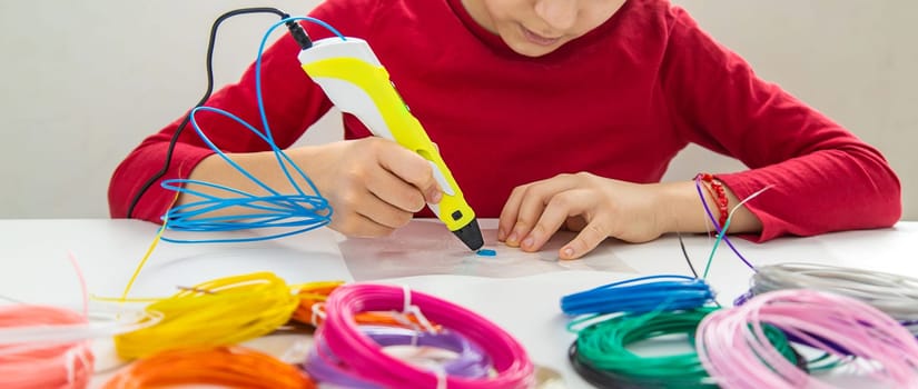 Child 3D drawings with a pen on the table. Selective focus. Kid.