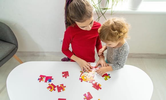 Children put together a puzzle on the table. Selective focus. Kid.