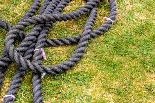Black rope on green grass for sports. Outdoor games and competitions. Physical education and strength.