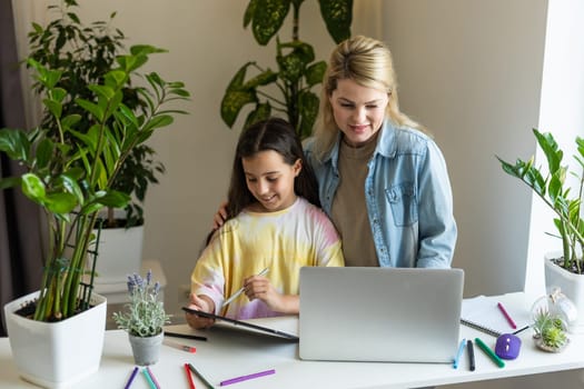 Back to school. Happy child and adult are sitting at desk. Girl doing homework or online education.