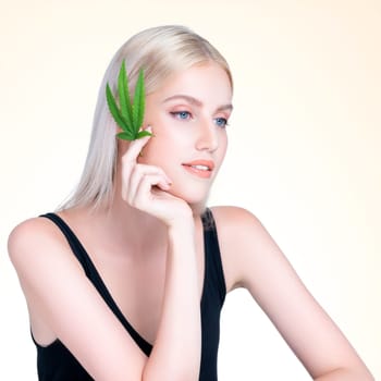 Personable beautiful white blond hair with perfect smooth makeup skin hold cannabis green hemp in isolated background for natural CBD skincare treatment with expressive facial and gesture expression.