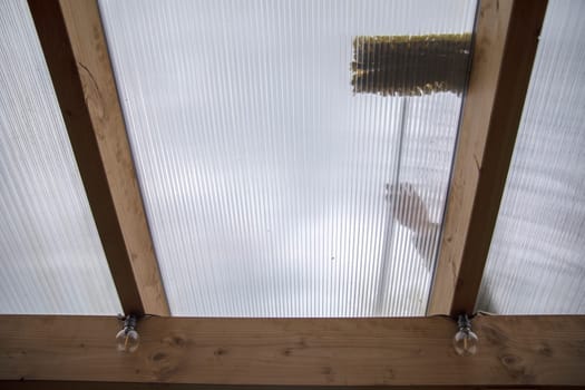 Washing the patio pergola roof cover made of aluminum. removing the dirty algae with brush soap and water close up in garden from a house terrace cleaning, workers, concept