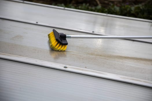 Washing the patio pergola roof cover made of aluminum. removing the dirty algae with brush soap and water close up in garden from a house terrace cleaning, workers, concept