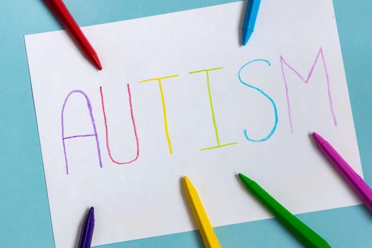 Text word autism on paper sheet written by colorful letter, on blue background