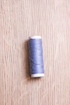 Coil of grey thread on a wooden table close up