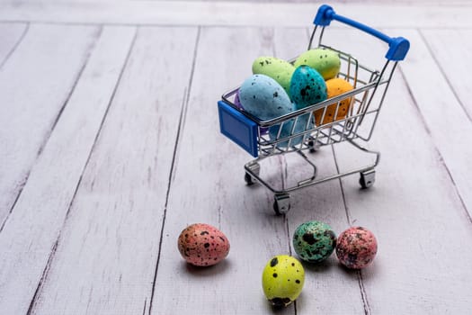 Colorful Easter eggs in a supermarket cart. Easter greeting card. Easter. Quail eggs. Spring holiday concept