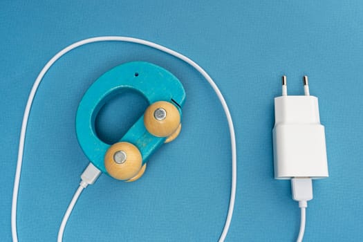 The phone charger is connected to a children's car on a blue background. A toy car with a charger and a connecting cable. The concept of an electric car. ecological transport