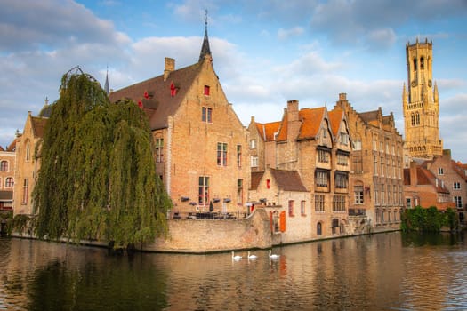 Flemish and ornate architecture of Bruges with canal and swans floating in a row, Flanders, Belgium