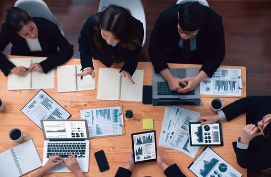 Top-view business team of financial data analysis meeting with business intelligence, report paper and dashboard on laptop for marketing strategy. Business people working together in office of harmony