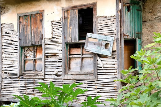 Facade of an old abandoned village house destroyed by time, close-up windows