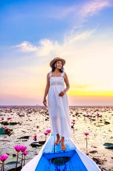 Asian women in a boat at the Beautiful Red Lotus Sea Kumphawapi is full of pink flowers in Udon Thani in Northern Thailand Isaan. Flora of Southeast Asia.