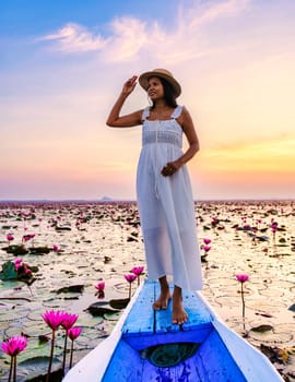 Asian women in a boat at the Beautiful Red Lotus Sea Kumphawapi is full of pink flowers in Udon Thani in Northern Thailand Isaan. Flora of Southeast Asia.