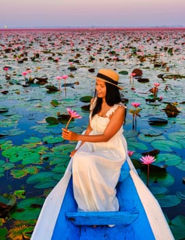 Asian women in a boat at the Beautiful Red Lotus Sea Kumphawapi is full of pink flowers in Udon Thani in northern Thailand. Flora of Southeast Asia.