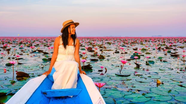 Thai women in a boat at the Beautiful Red Lotus Sea Kumphawapi is full of pink flowers in Udon Thani in northern Thailand. Flora of Southeast Asia.