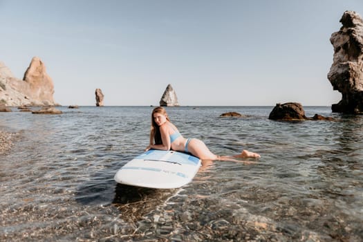 Close up shot of happy young caucasian woman looking at camera and smiling. Cute woman portrait in bikini posing on a volcanic rock high above the sea