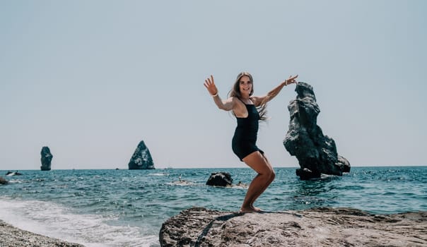 Woman travel sea. Young Happy woman in a long red dress posing on a beach near the sea on background of volcanic rocks, like in Iceland, sharing travel adventure journey