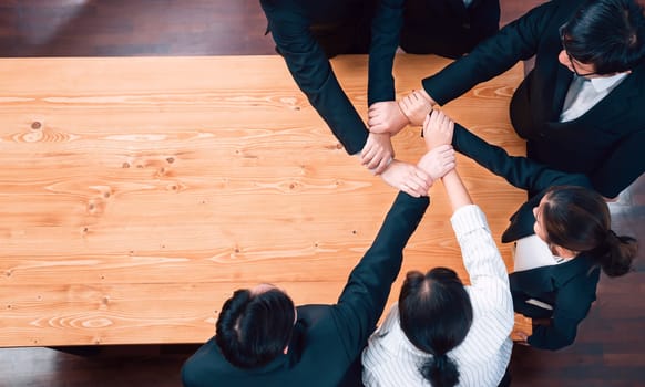 Top view cohesive group of business people join hands stack together, form circle over meeting table for copyspace. Colleagues working to promote harmony and synergy team building concept in workplace