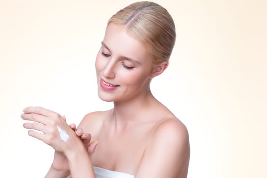 Personable woman applying moisturizer cream on her hand for perfect skincare treatment concept in isolated background. Beauty care cream applying on body by female model with soft natural makeup.